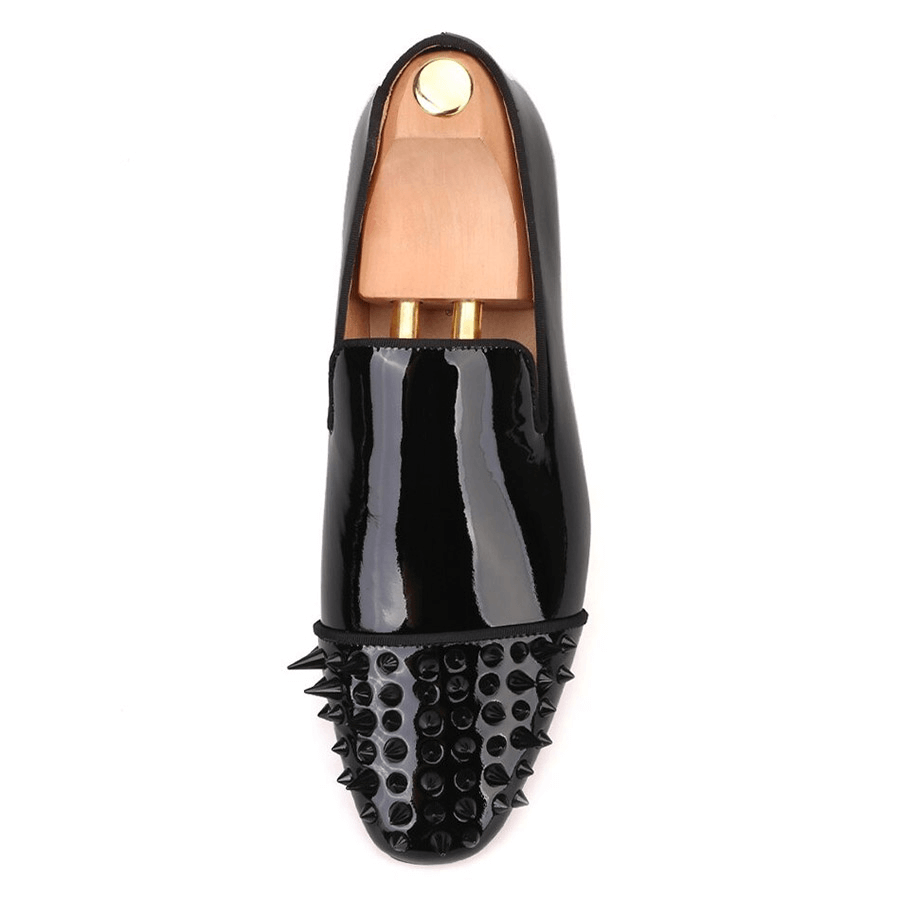 Flat lay overhead view of single black patent leather gothic loafer with spike-studded toe cap and slip-on design