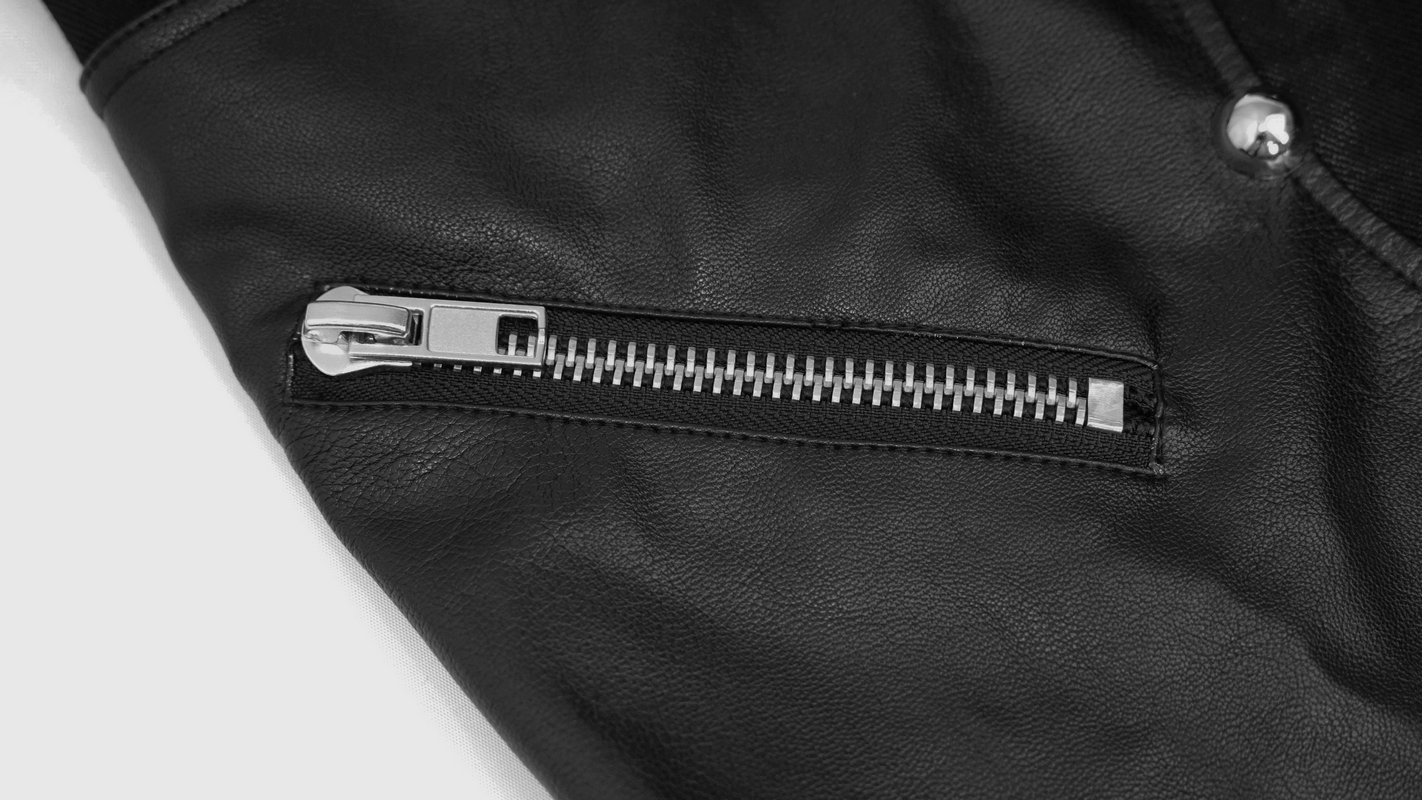 Black gothic leather rivet pants - front three-quarter view showing asymmetric design and riveted panel construction