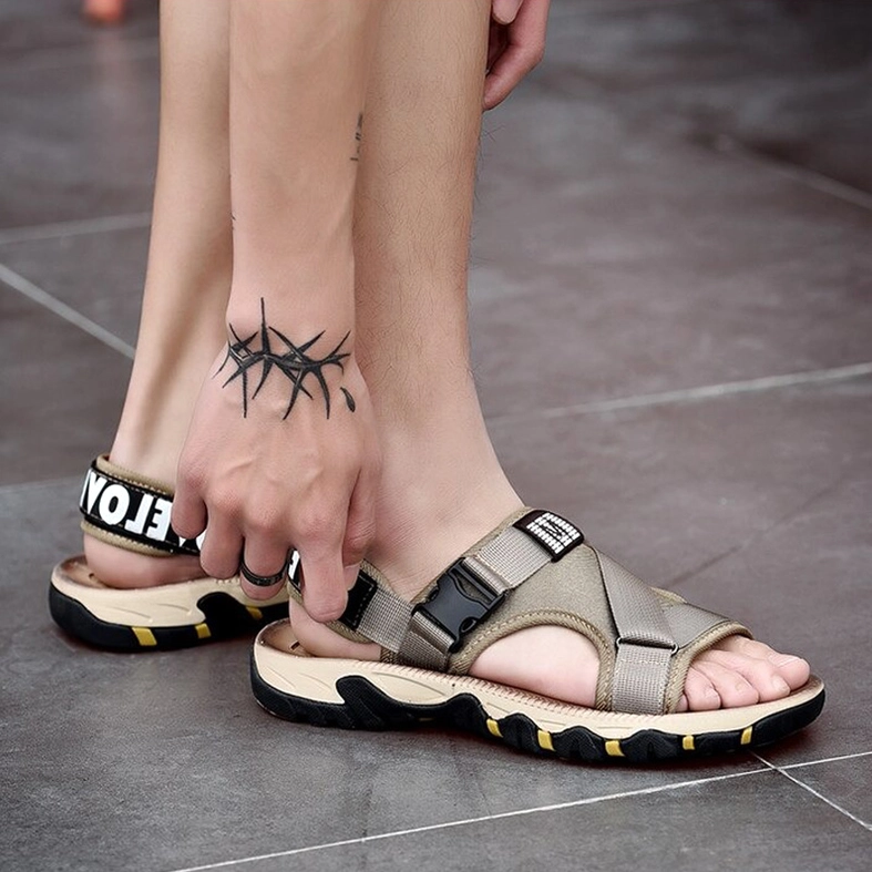 Male model wearing khaki gothic sandals showing foot tattoo and heel strap letter print detail