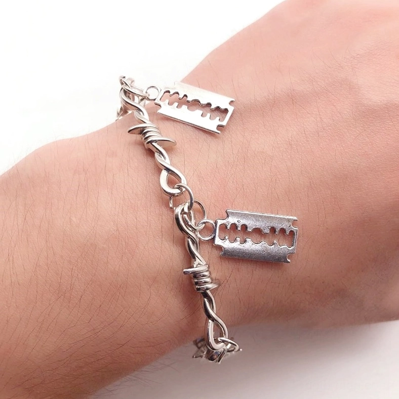 Barbed wire razor blade gothic bracelet worn on hand, front close-up showing two razor pendants on twisted barbed chain design