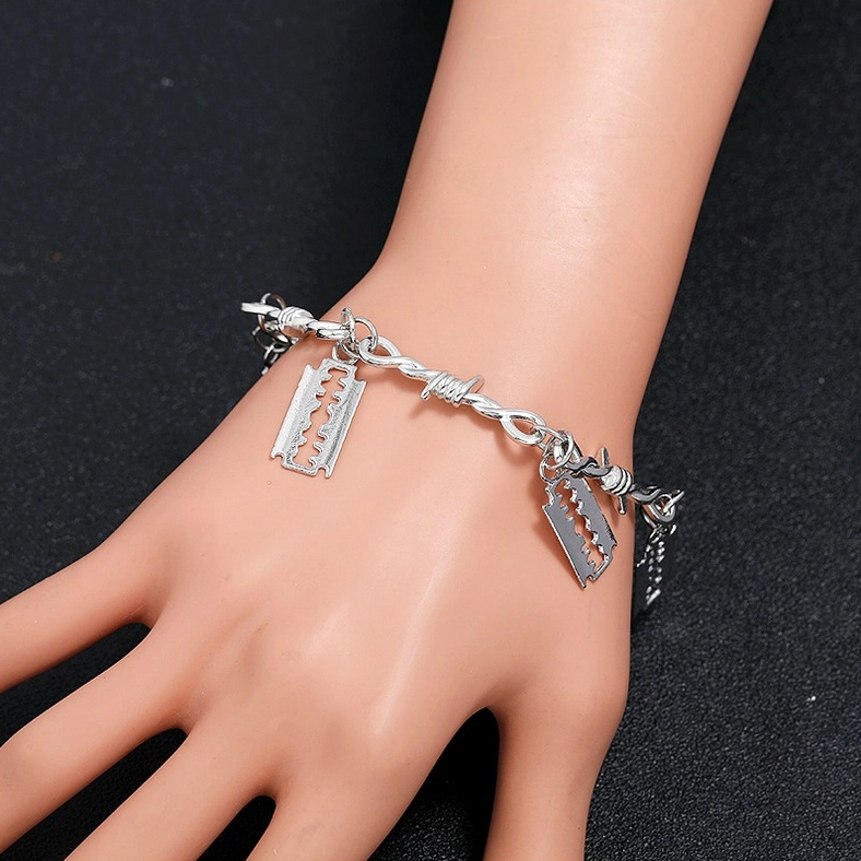 Barbed wire razor blade gothic bracelet worn on mannequin hand, side profile showing adjustable tail chain and silver-tone finish