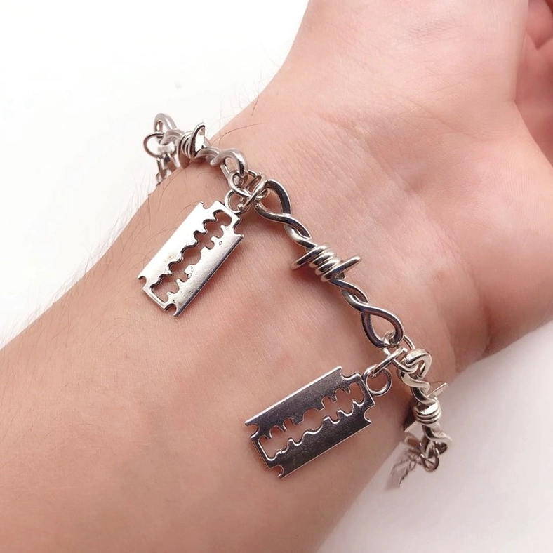 Barbed wire razor blade gothic bracelet on wrist, oblique angle view highlighting silver metal finish and distinct razor charms