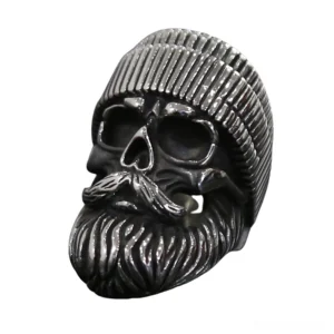 Bearded skull biker ring with detailed facial hair and ribbed beanie hat, left front three-quarter view on white background showing dark stainless steel gothic finish