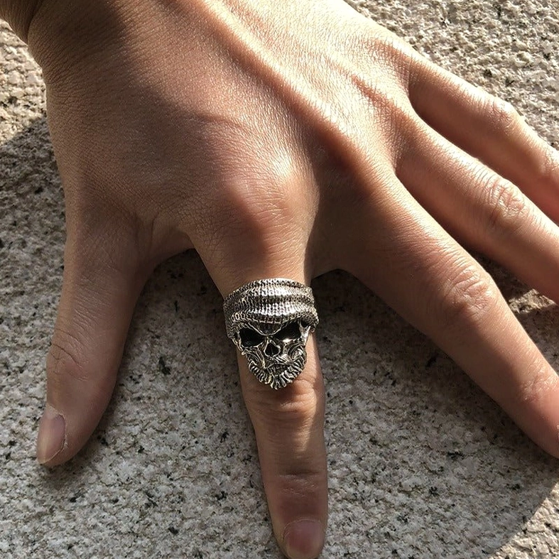Bearded skull ring worn on hand – top-down view showing perfect fit on index finger with concrete background
