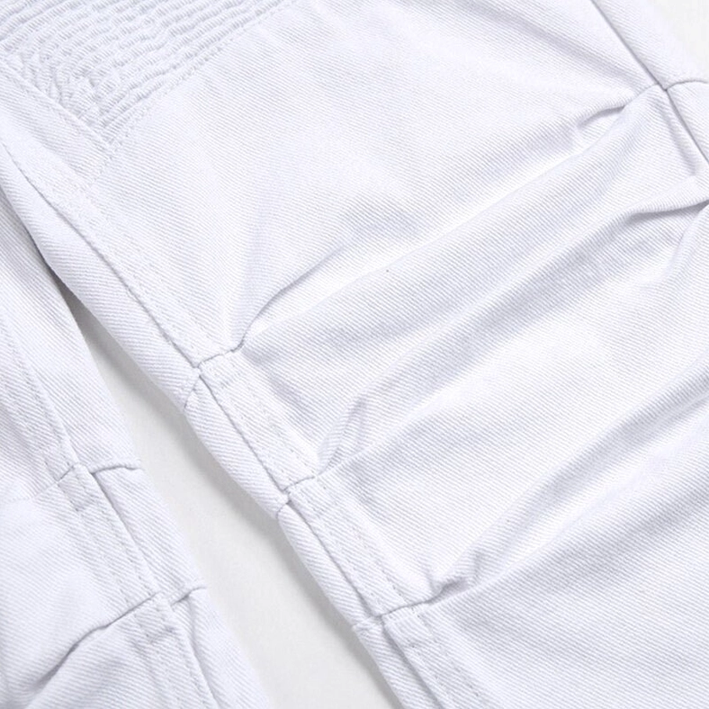 Macro detail of white gothic pleated knee panels showing stitched architectural design and denim texture