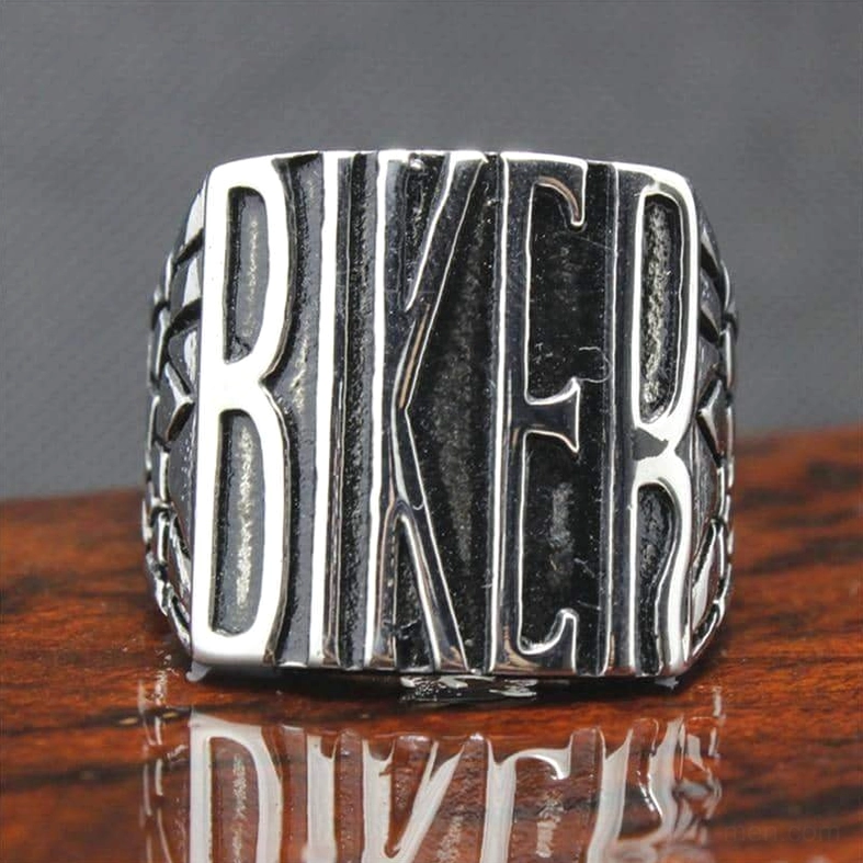 Biker statement ring displaying polished silver finish with embossed BIKER lettering on wooden tabletop with reflective surface