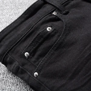 Close-up detail of black denim jeans pocket with metal rivets and reinforced stitching, functional pocket trim for gothic alternative wear