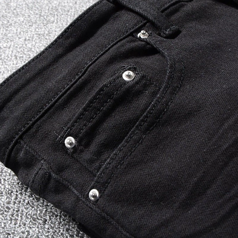 Close-up detail of black denim jeans pocket with metal rivets and reinforced stitching, functional pocket trim for gothic alternative wear