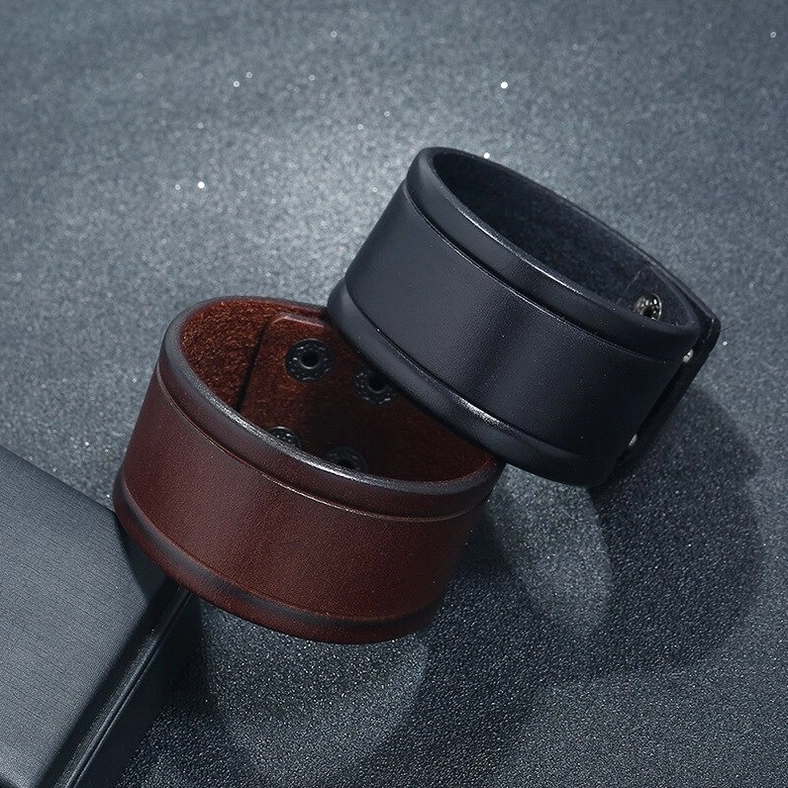 Black and brown wide leather gothic cuff bracelets flat lay comparison with display stand
