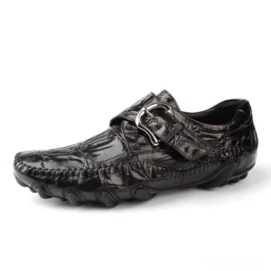 Black crocodile leather gothic loafers with metal buckle strap, three-quarter side view showcasing textured pattern