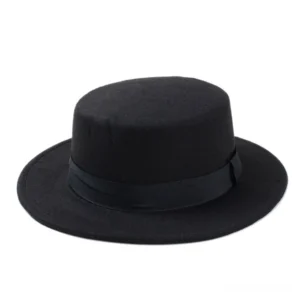 Black flat top fedora in wool felt with structured crown viewed from front overhead angle, gothic alternative hat style