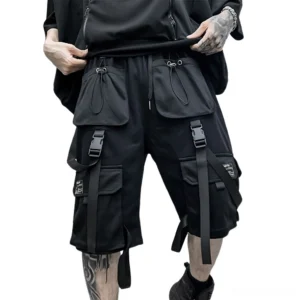 Black gothic cargo shorts front view with tactical webbing straps and multiple deep pockets on tattooed male model wearing combat boots