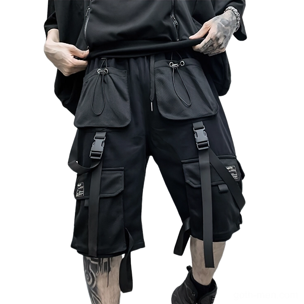Black gothic cargo shorts front view with tactical webbing straps and multiple deep pockets on tattooed male model wearing combat boots