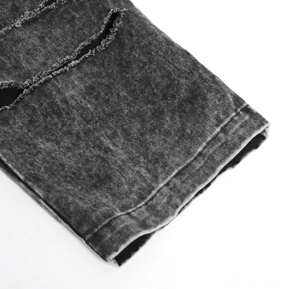 Black distressed gothic jeans leg opening close-up, acid-washed finish with multiple ripped sections and chain decoration through eyelets