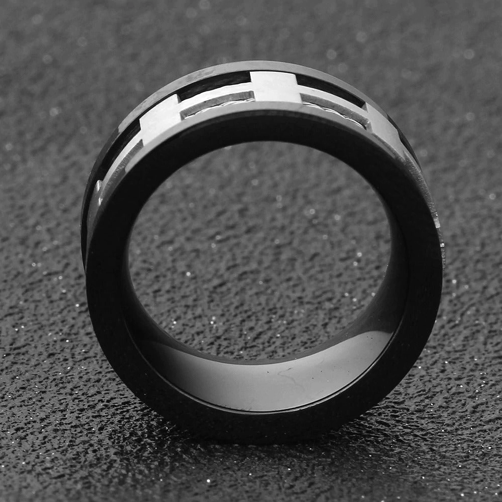 Top-down view of black gothic cross ring showing matte finish and dual-tone inlay design on dark textured background