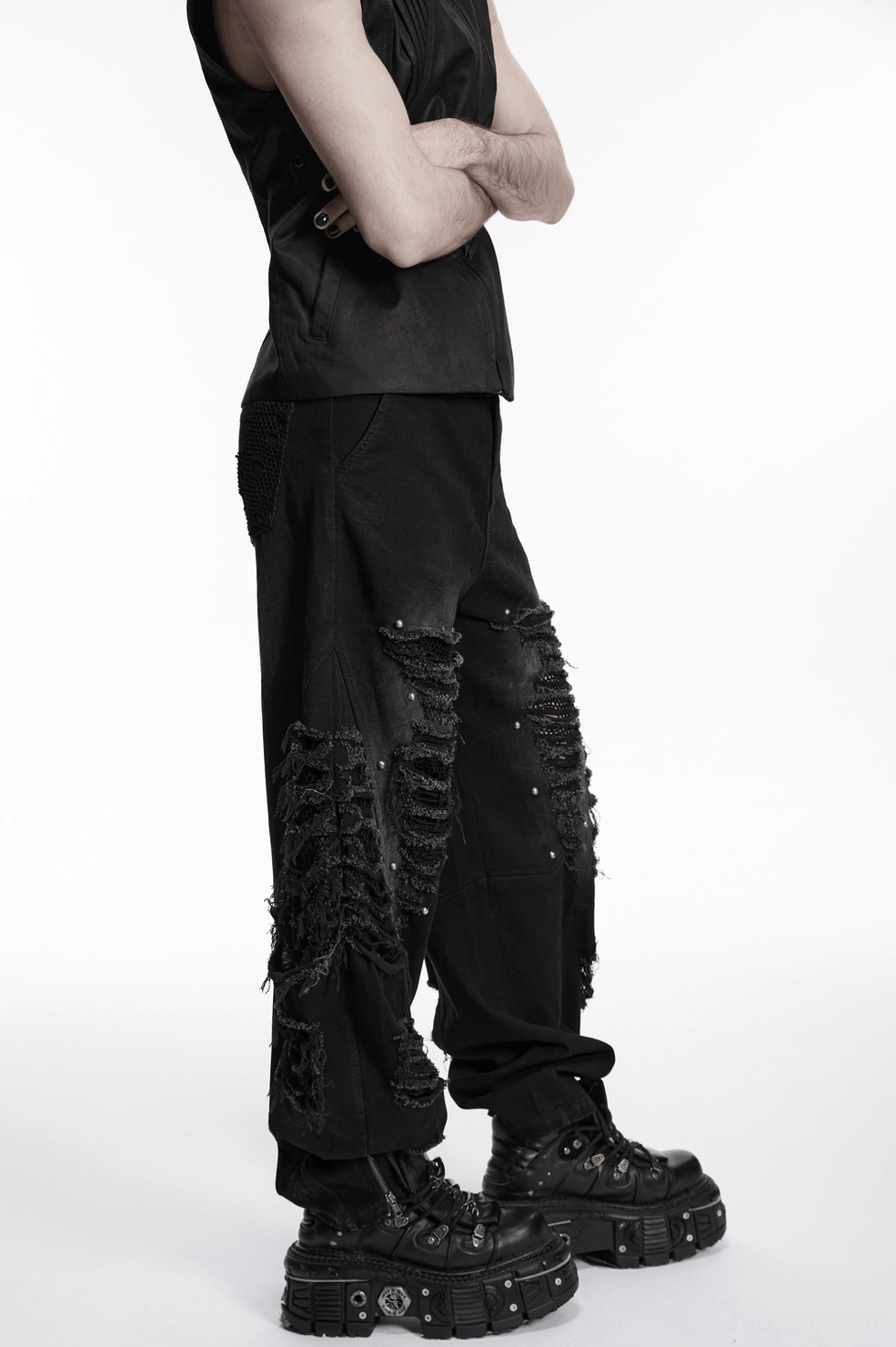 Black distressed denim pants male model angle shot showing knee mesh rips metal studs