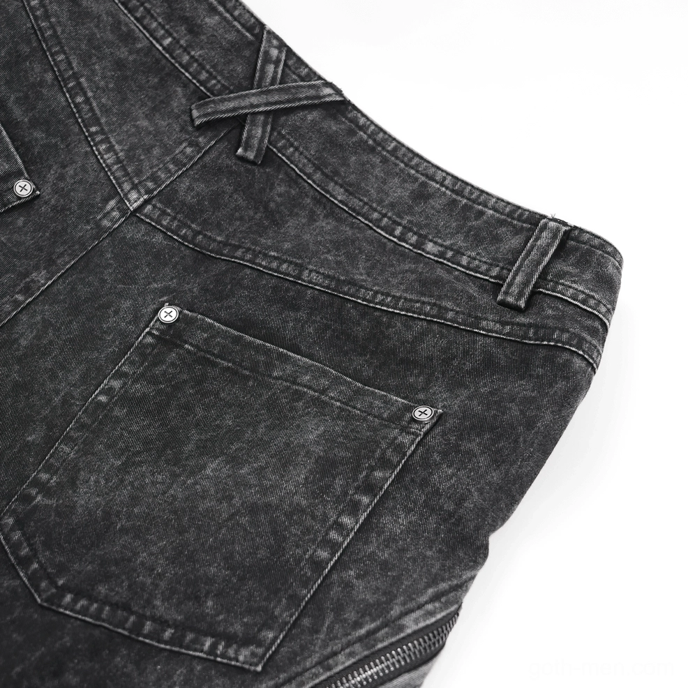 Detail shot of distressed black denim showing strategic tears, frayed edges, and industrial aesthetic