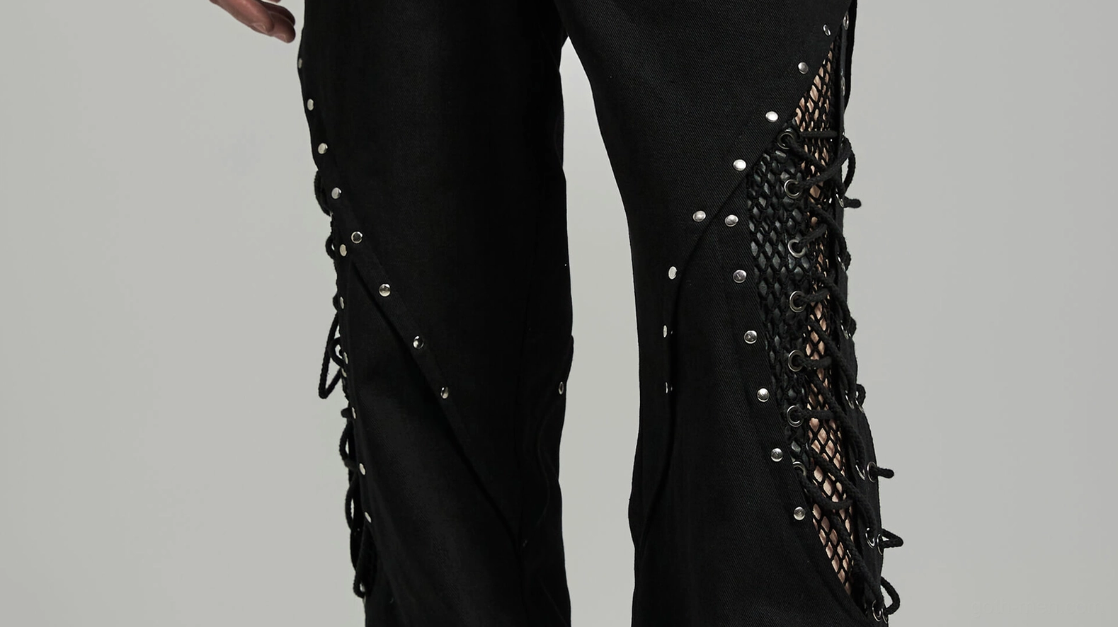 Full length view of black gothic flare pants with mesh rivet details on model