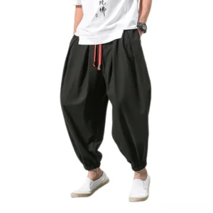 Black gothic harem pants men cropped with red drawstring and elastic ankle cuffs worn by male model front view