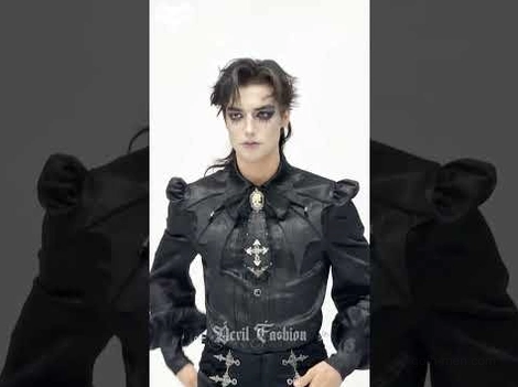 Male model full torso wearing black gothic jabot choker with multiple cross charms and structured shoulders on dark background