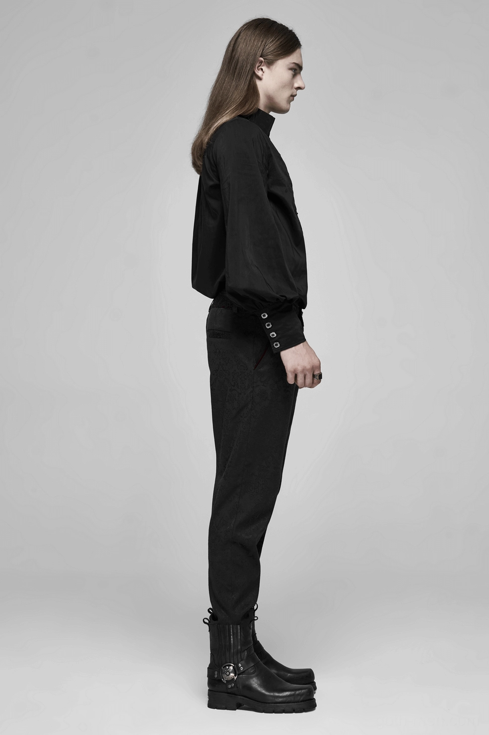 Black gothic jacquard slim-fit pants front waist and hip area showing fitted silhouette, metal buttons, and intricate fabric pattern