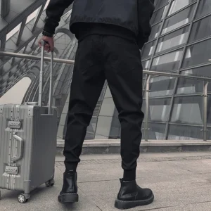 Black cargo pants rear view outdoor modern setting with rolling luggage styling