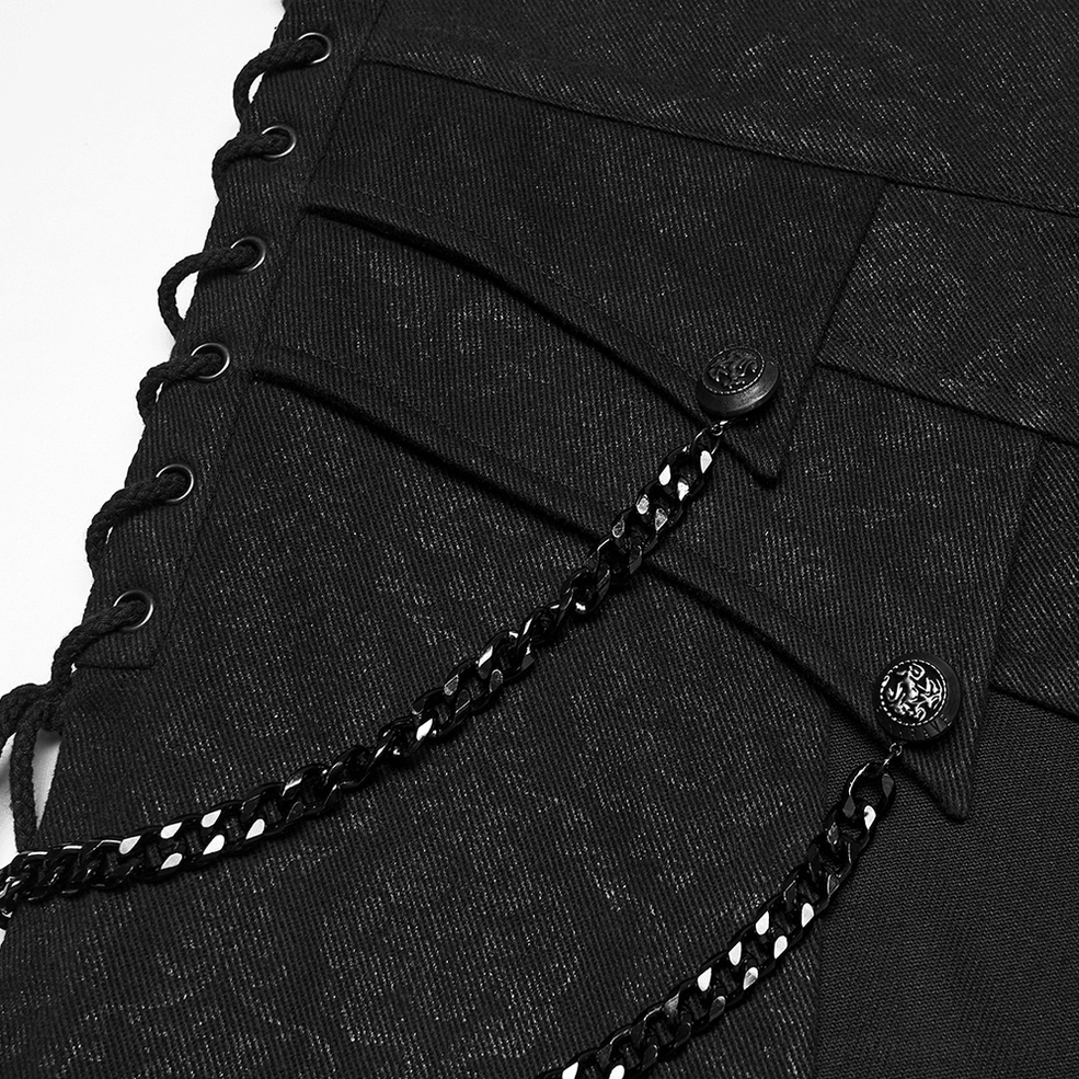 Black gothic kilt panel hardware featuring metal chain decorations with branded buttons and layered panel construction macro close-up
