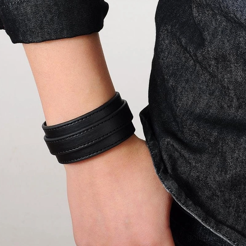 Black gothic leather cuff bracelet worn on wrist, adjustable double-layer strap, close-up styling view with denim