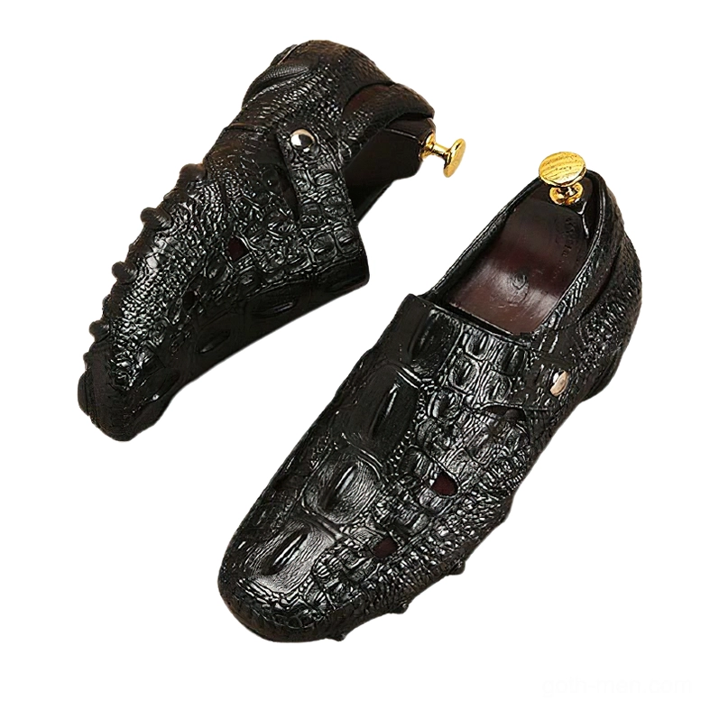 Black gothic crocodile-embossed leather loafers at angled side view with shoe trees inserted, displaying non-slip rubber outsole and reptilian texture pattern