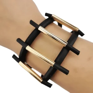 Black gothic magnetic rubber bracelet worn on wrist, side close-up showing dual-layer structure with gold metal ladder bars and geometric design