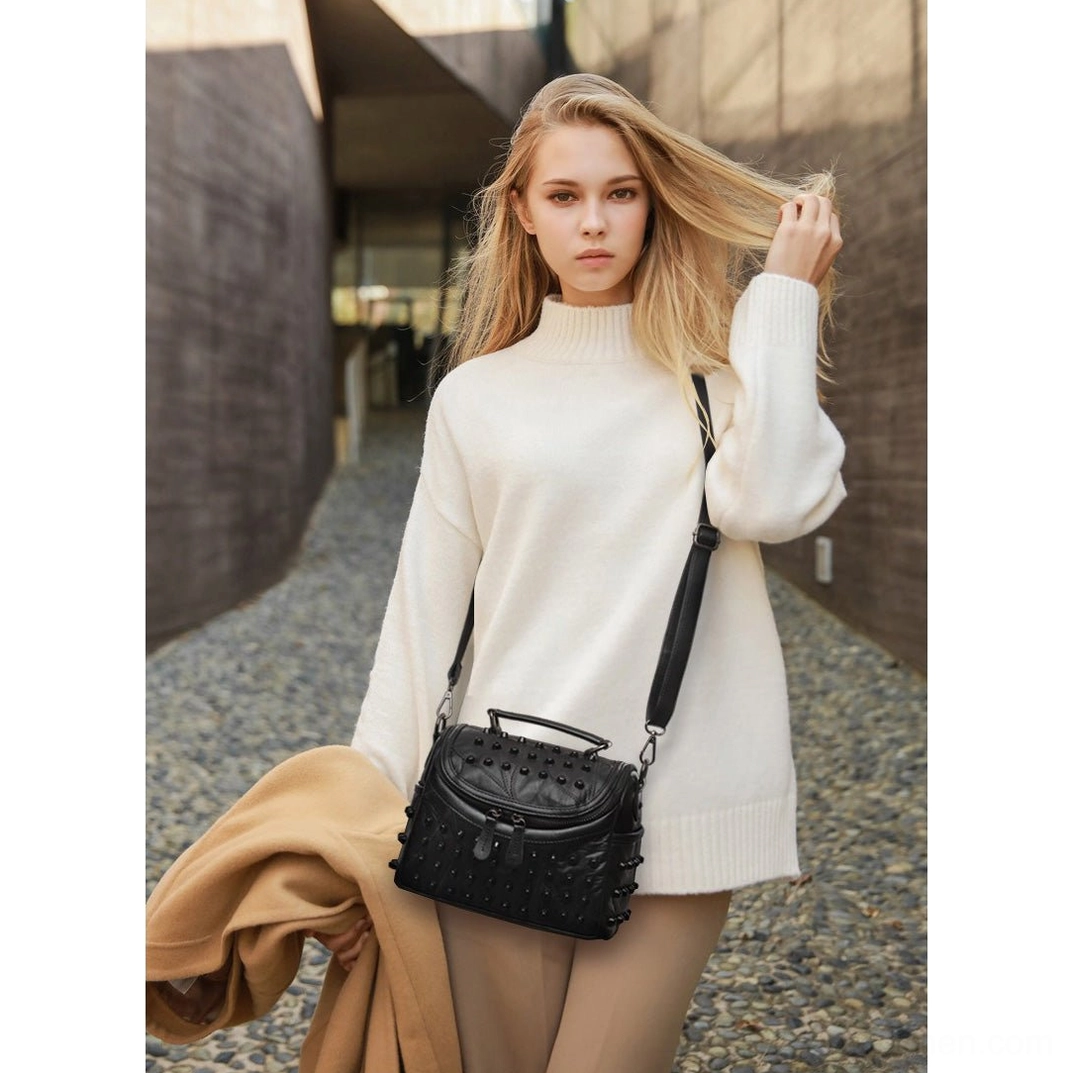 Black leather messenger bag with metal studs worn crossbody demonstrating authentic alternative fashion style