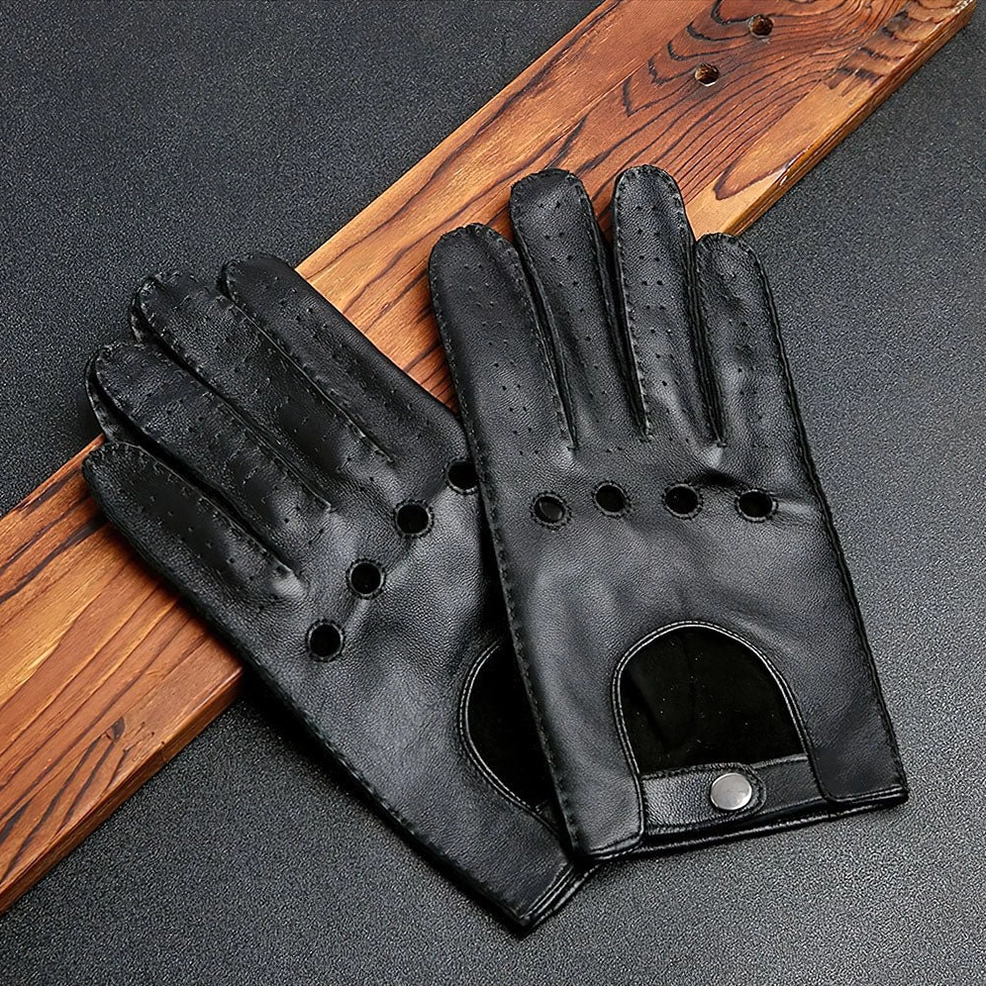 Black gothic leather motorcycle gloves with ventilated perforations and wrist snap fastener on textured background