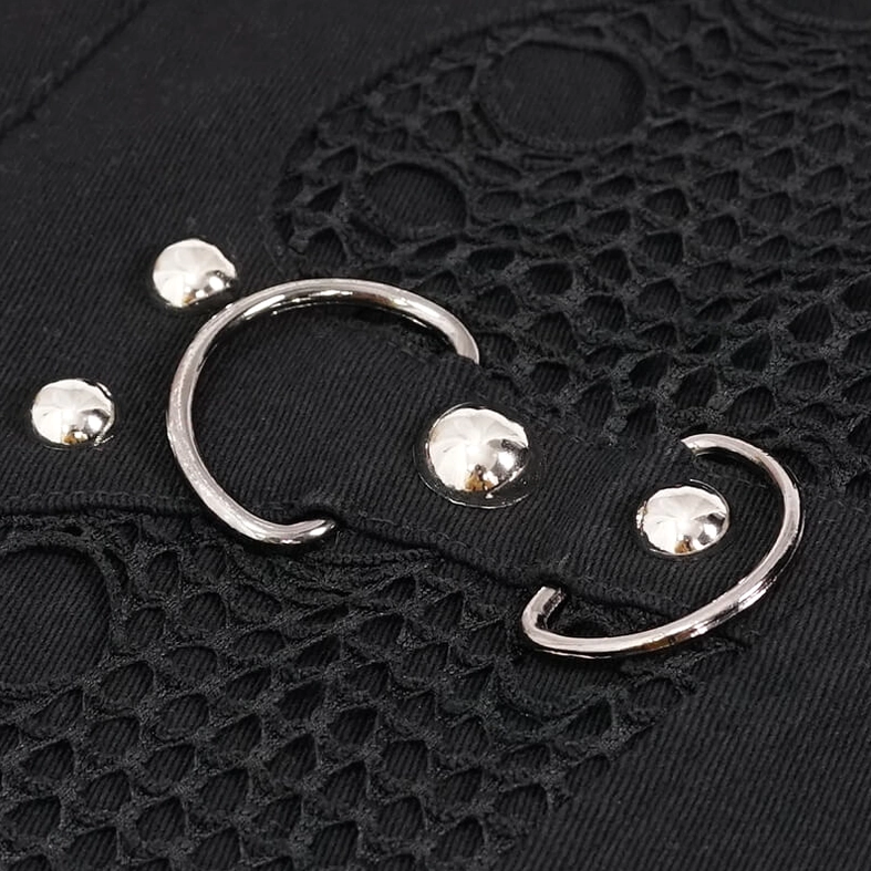 Close-up top view of black gothic punk vest metal hardware showing D-rings, rivet studs, and mesh fabric integration detail