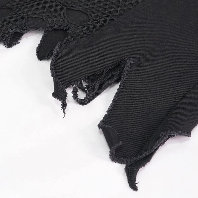 Close-up detail of black gothic punk vest hem showing frayed torn edge, twill fabric weave, and mesh panel junction on white background