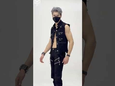 Black gothic punk cropped vest side view on masked male model with grey hair, emphasizing metal hardware details and fitted silhouette