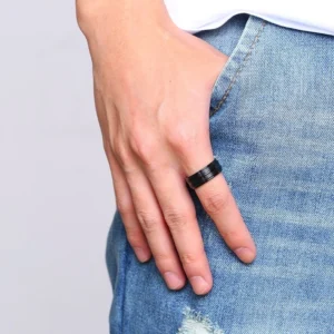 Men's black metal gothic ring worn on index finger close-up with denim background, alternative jewelry styling