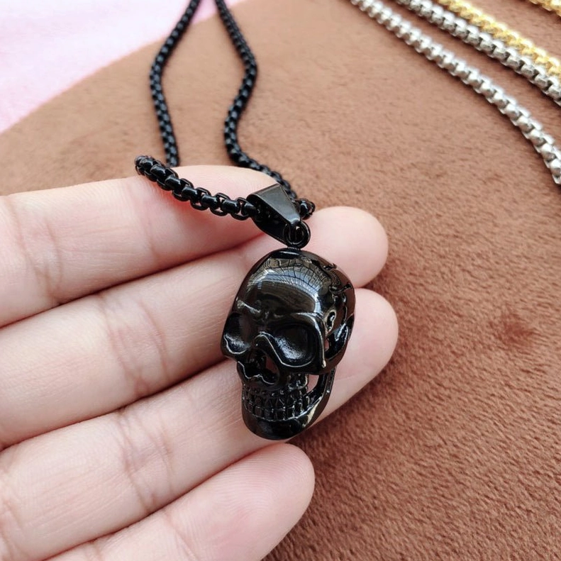 Black skull pendant necklace worn close-up side view on hand, showing detail and shine