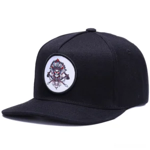 Black gothic snapback baseball cap with embroidered native skull motif, front three-quarter angle view showcasing round skull patch design