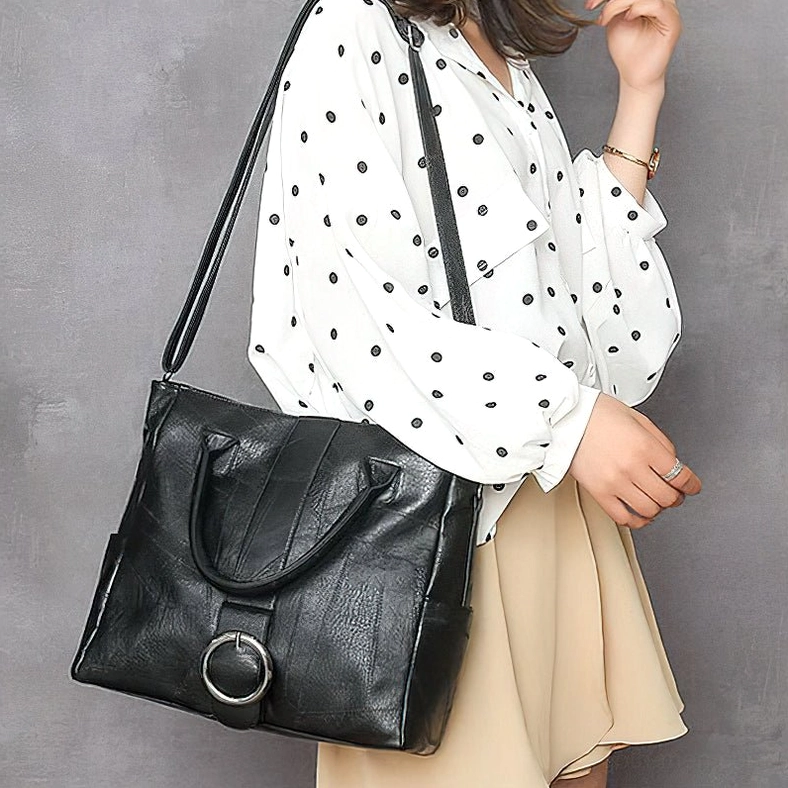 Woman wearing black gothic leather crossbody tote bag - side casual styling with polka dot shirt