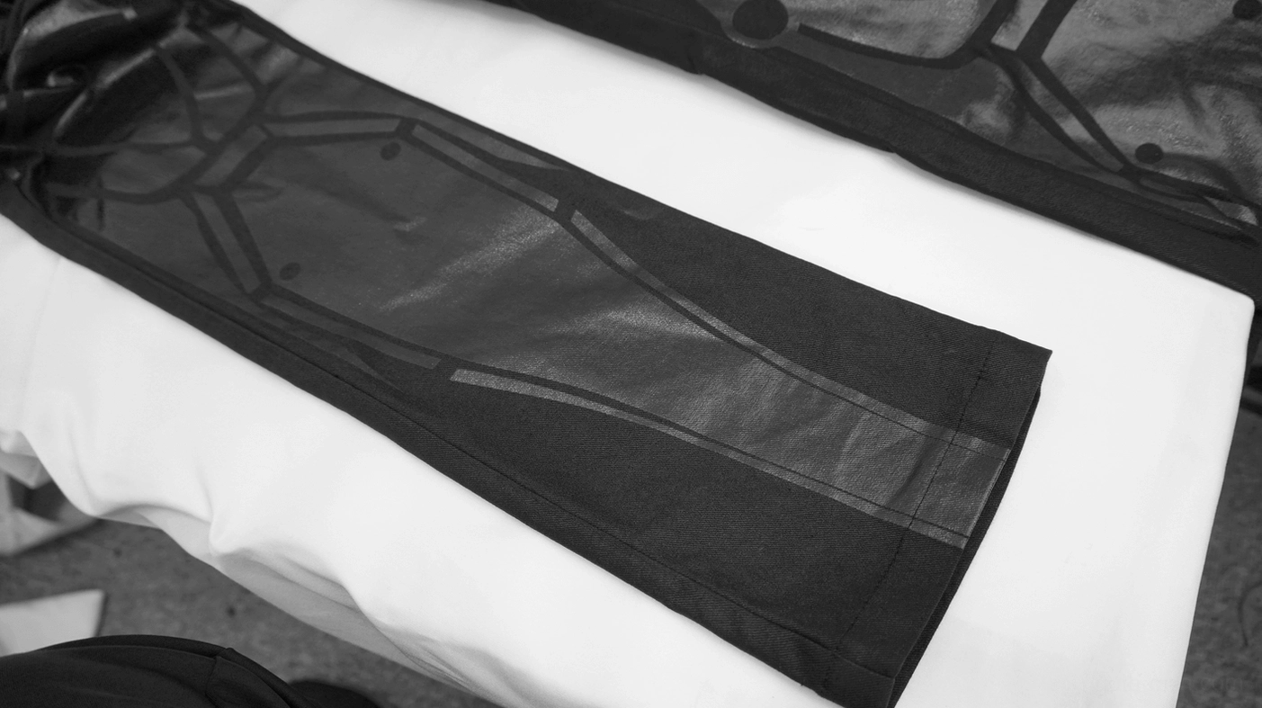 Close-up detail of geometric circuit-style print on black gothic trouser fabric