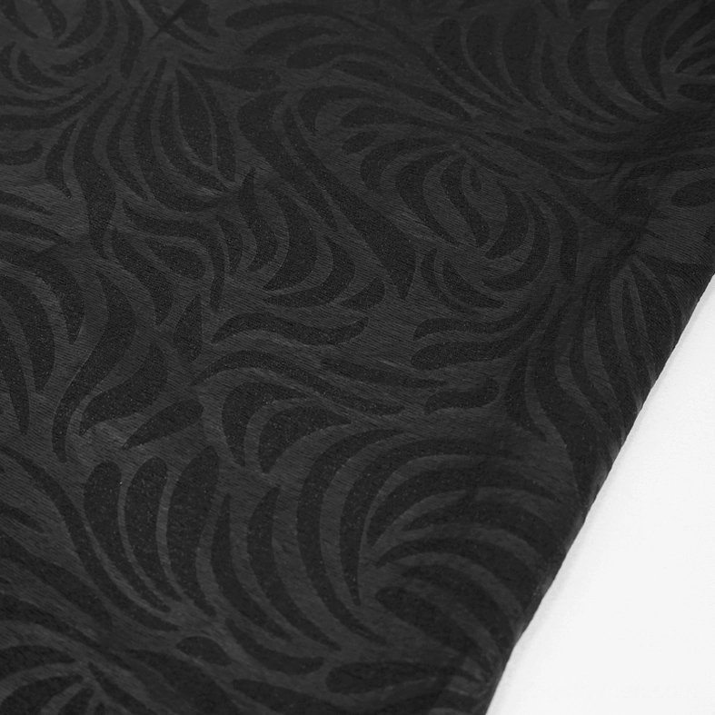 Macro close-up of black jacquard fabric texture showing swirling dark pattern on sheer transparent mesh base, gothic design element