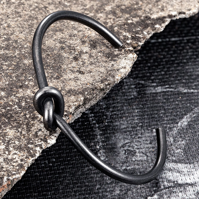 Side angle shot of matte black knotted open cuff gothic bracelet showing three-dimensional wire construction