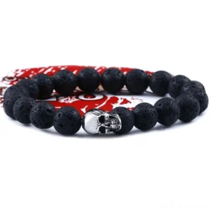 Black lava stone skull bracelet flat lay with stainless steel skull charm on red fabric background