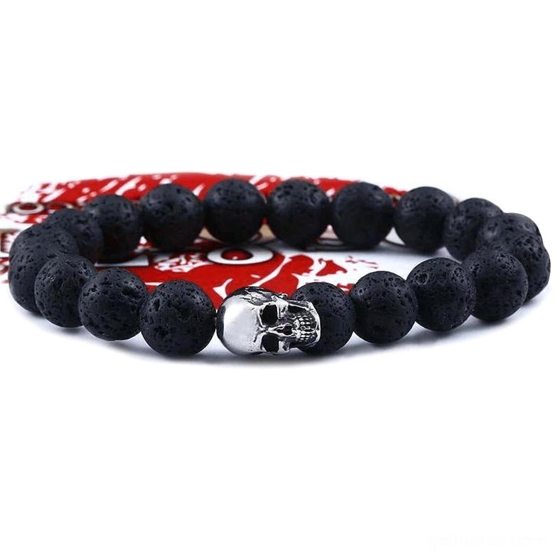 Black lava stone skull bracelet flat lay with stainless steel skull charm on red fabric background