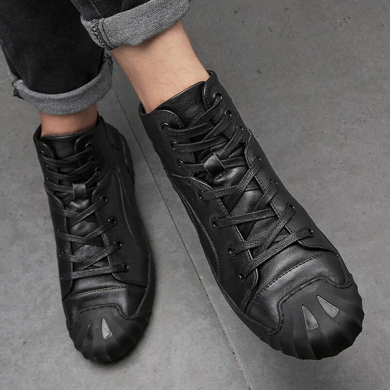 Low angle front view of black leather high-top gothic sneaker on male model with shell toe and matte finish
