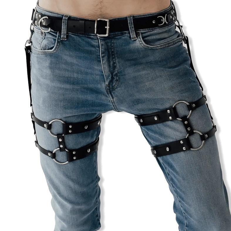Black faux leather thigh harness styled with blue jeans, front view showing industrial aesthetic and metal buckles on casual wear