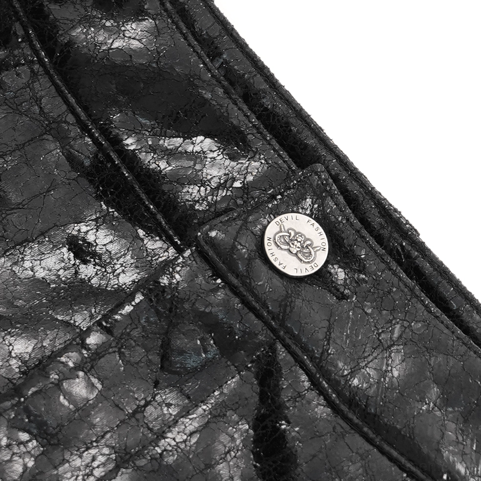 Close-up detail shot of cracked glossy black faux leather material with branded metal button accent