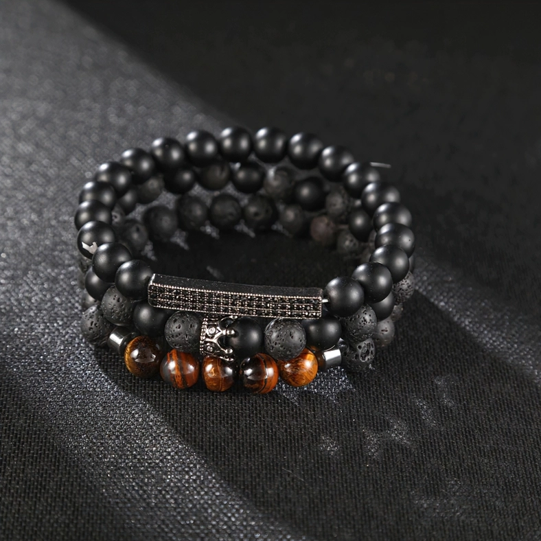 Black onyx gothic bracelet flat lay photography featuring engraved metal plate and crown charm detail, dark fabric background jewelry display