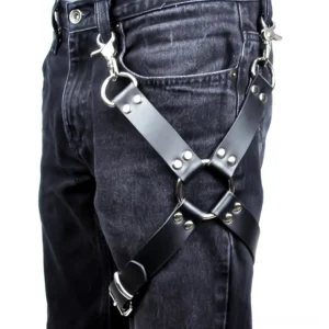 Black PU leather leg harness with geometric crisscross straps and silver rivets, detailed side view on denim