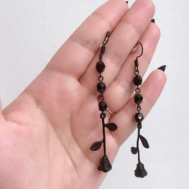 Black gothic rose drop earrings worn on female hand with dark nail polish, side close-up view